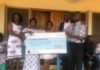 Acting Deputy Head of Business Development at First Insurance, Dela Hosu, presenting the cheque to the family