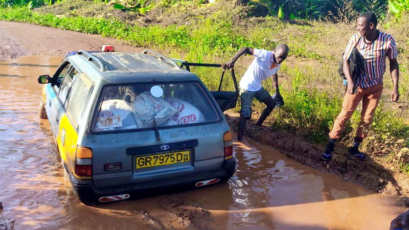 Passengers get down from car, attempting to aid driver push car out of mud