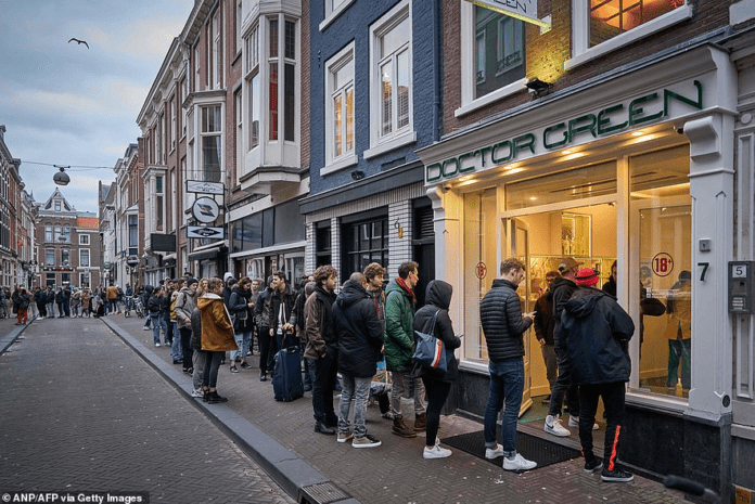 A queue of people line up outside a shop called Doctor Green - one of Holland's famous 'coffee shops' - in the Hague yesterday after the Dutch government announced that many businesses were closing over coronavirus fears