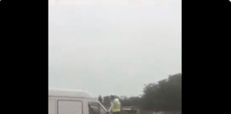 Police Officer stands on the vehicle's bonnet to stop driver from moving