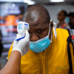 Man being checked with a gun thermometer at a checkpoint because of Coronavirus