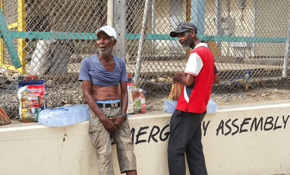 Two old men receive items from Amadia Foundation