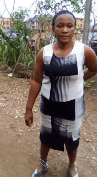 Ngozi Chukwuani with the padlock on her feet/ Woman rescued after being chained to pillar for 10 hours by her husband