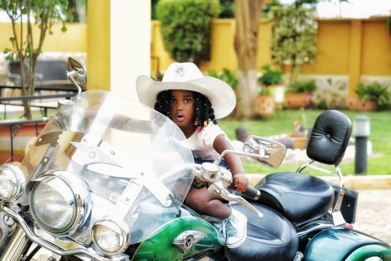 Gifty Anti's daughter, Nyame Anuonyam poses on father's motorbike