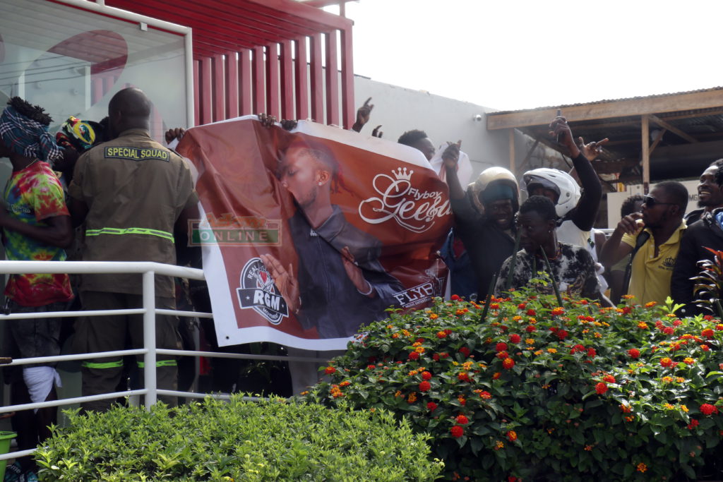 Fans of Flyboy Geesus holding up his banner at the forecourt of Multimedia - Kokomlemle