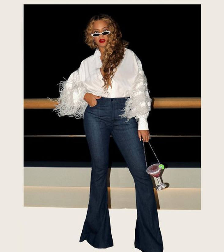  Beyonce oozed vintage glamor in a white unbuttoned shirt with unruly feathers on its sleeves and dark bell bottoms.  