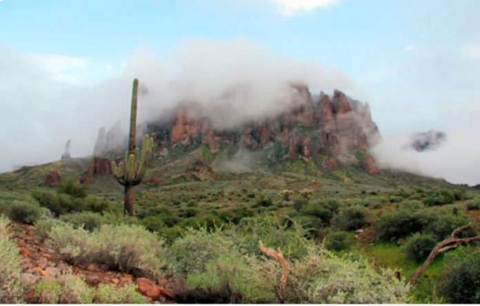 In this Jan. 29, 2015, file photo, low-hanging winter clouds hug part of Superstition Mountain in Lost Dutchman State Park in Apache Junction, Ariz.