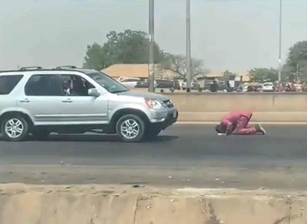 Man kneels down, prays in the middle of busy highway with his 'Holy Book'