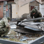 Police officers inspect the remains of a missile that fell in the street, after Russian President Vladimir Putin authorized a military operation in eastern Ukraine, in Kyiv, Ukraine February 24, 2022 [Valentyn Ogirenko/Reuters]
