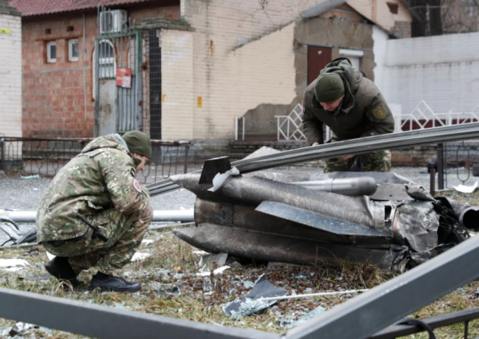 Police officers inspect the remains of a missile that fell in the street, after Russian President Vladimir Putin authorized a military operation in eastern Ukraine, in Kyiv, Ukraine February 24, 2022 [Valentyn Ogirenko/Reuters]