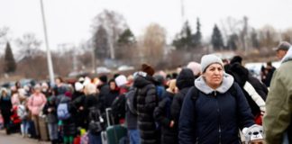 People wait to board a bus at the border checkpoint in Medyka after fleeing Ukraine - Reuters/Yara Nardi