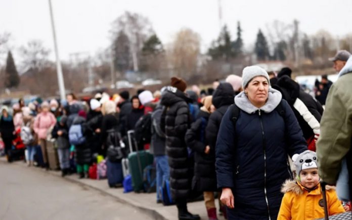 People wait to board a bus at the border checkpoint in Medyka after fleeing Ukraine - Reuters/Yara Nardi