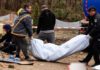 Police members carry the body of a civilian, after they exhumed him along with another body from a well at the fuel station in Buzova (Image: REUTERS)