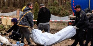 Police members carry the body of a civilian, after they exhumed him along with another body from a well at the fuel station in Buzova (Image: REUTERS)