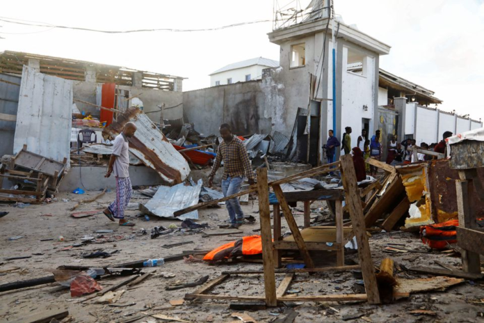 Bystanders walk through the scene of bombing at a seaside restaurant at Liido beach in Mogadishu, Somalia April 23, 2022. REUTERS/Feisal Omar