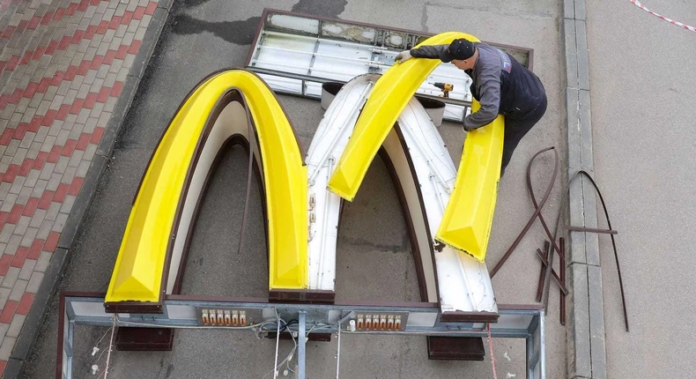 A worker dismantles the McDonald's Golden Arches logo at a drive-through restaurant in Kingisepp, Russia.