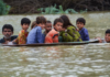 A man helps children navigate floodwaters using a satellite dish in Balochistan, Pakistan, on Friday, August 26.