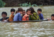 A man helps children navigate floodwaters using a satellite dish in Balochistan, Pakistan, on Friday, August 26.