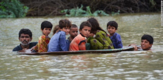 A man helps children navigate floodwaters using a satellite dish in Balochistan, Pakistan, on Friday, August 26.