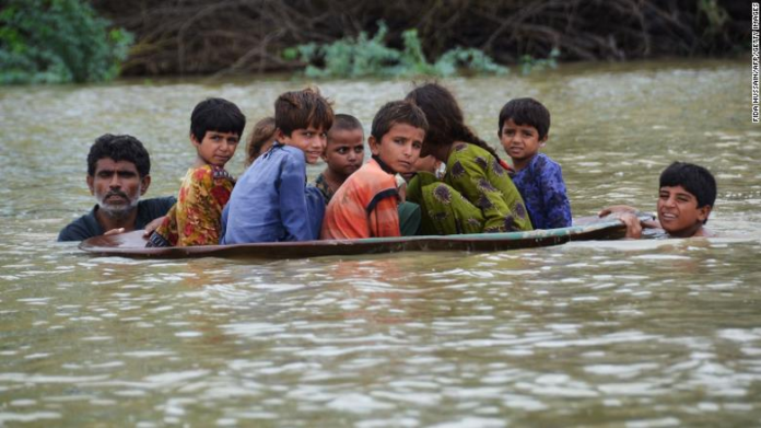 A man helps children navigate floodwaters using a satellite dish in Balochistan, Pakistan, on Friday, August 26. A man helps children navigate floodwaters using a satellite dish in Balochistan, Pakistan, on Friday, August 26.