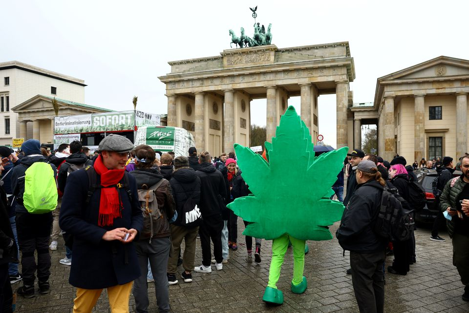 A person dressed in a costume depicting a cannabis leaf walks among marijuana activists to mark the annual world cannabis day and to protest for legalization of marijuana, in front of the Brandenburg Gate, in Berlin, Germany, April 20, 2022. REUTERS/Lisi Niesner