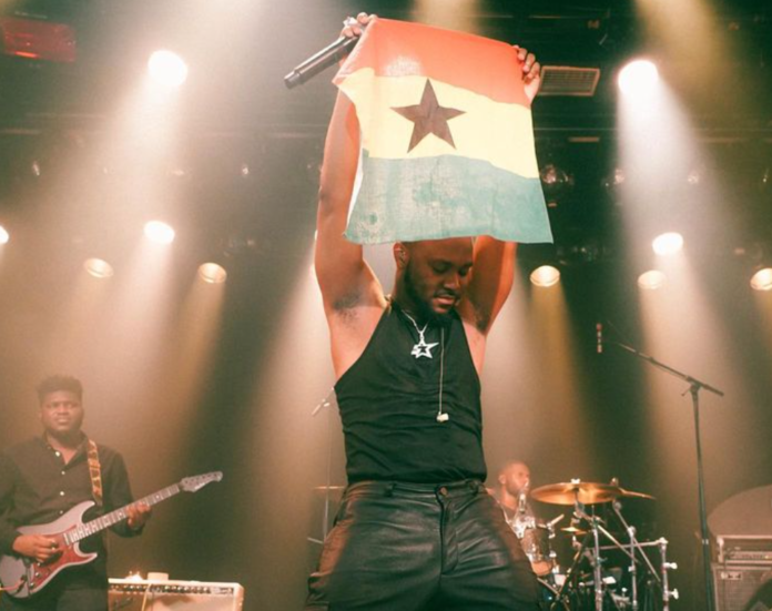 King Promise projects a Ghana flag during one of his 5 Star world tour performances in Europe