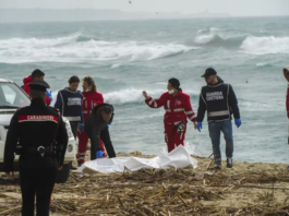 Italian Red Cross volunteers and coast guards recover a body after a migrant boat broke apart in rough seas, at a beach near Cutro, southern Italy, on Feb. 26, 2023. AP/Antonino Durso/LaPress