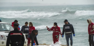 Italian Red Cross volunteers and coast guards recover a body after a migrant boat broke apart in rough seas, at a beach near Cutro, southern Italy, on Feb. 26, 2023. AP/Antonino Durso/LaPress