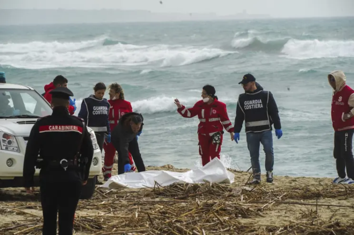 Italian Red Cross volunteers and coast guards recover a body after a migrant boat broke apart in rough seas, at a beach near Cutro, southern Italy, on Feb. 26, 2023. AP/Antonino Durso/LaPress