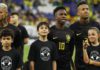 Vinicius Jr (centre) and his Brazil team-mates wore black kits for the first half of last month's friendly against Guinea while mascots wore t-shirts that read 'with racism there is no game'