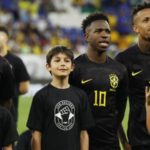 Vinicius Jr (centre) and his Brazil team-mates wore black kits for the first half of last month's friendly against Guinea while mascots wore t-shirts that read 'with racism there is no game'