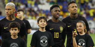 Vinicius Jr (centre) and his Brazil team-mates wore black kits for the first half of last month's friendly against Guinea while mascots wore t-shirts that read 'with racism there is no game'