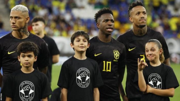 Vinicius Jr (centre) and his Brazil team-mates wore black kits for the first half of last month's friendly against Guinea while mascots wore t-shirts that read 'with racism there is no game'