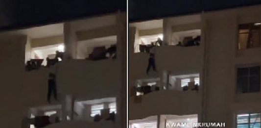 The victim hanging on the building while his colleagues are trying to save him