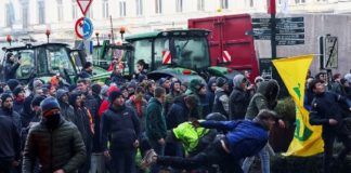 A person throws eggs towards the police officers as Belgian farmers use their tractors to block the European Union headquarters, as they protest over price pressures, taxes and green regulation, grievances shared by farmers across Europe, on the day of the EU summit in Brussels, Belgium February 1, 2024. REUTERS