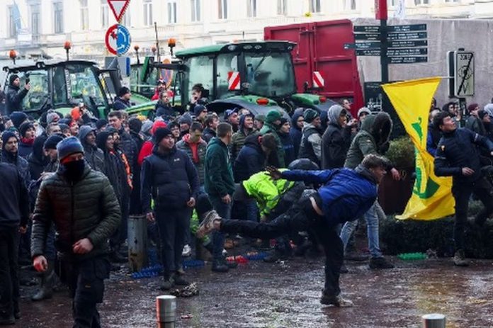 A person throws eggs towards the police officers as Belgian farmers use their tractors to block the European Union headquarters, as they protest over price pressures, taxes and green regulation, grievances shared by farmers across Europe, on the day of the EU summit in Brussels, Belgium February 1, 2024. REUTERS