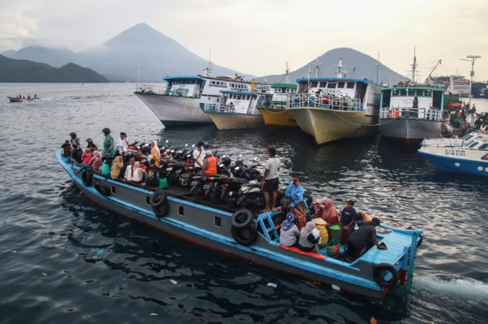 People travel on a wooden boat with motor scooters to Tidore Island ahead of Eid al-Fitr, which marks the end of the Muslim fasting month of Ramadan, at Bastiong port in Ternate, North Maluku, on 7 April 2024. Azzam Risqullah / AFP