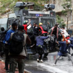 Demonstrators try to obstruct a police vehicle as police use water cannons to disperse protesters during a demonstration against Kenya's proposed finance bill 2024/2025 in Nairobi, Kenya, June 25, 2024. REUTERS/Monicah Mwangi