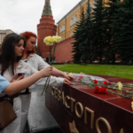 EPA/ People lay flowers as tribute to the victims of Sunday's attack on a memorial bearing the word Sevastopol in Moscow