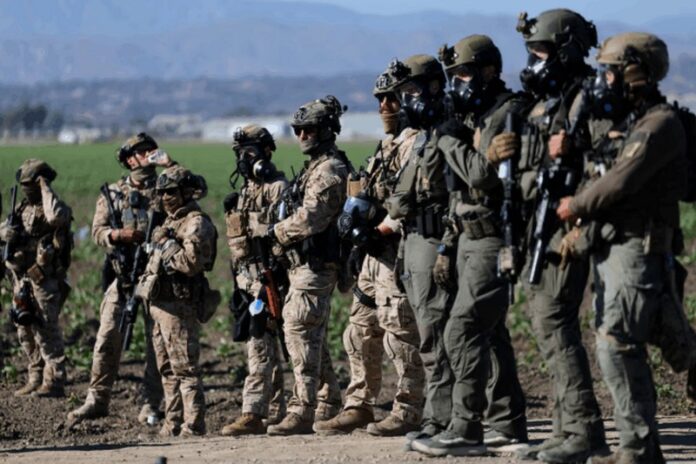 U.S. federal agents stand guard while blocking a road leading to an agricultural facility where U.S. federal agents and immigration officers carried out an operation, in Camarillo, California